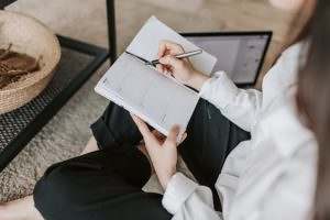 crop woman writing in notebook at home